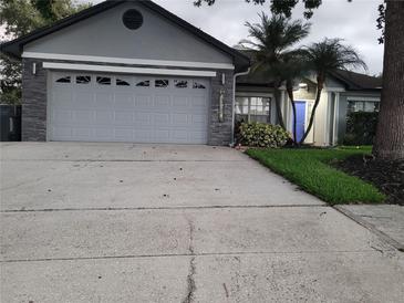 Charming single-Gathering home showcasing a manicured lawn, stone accents, and a two-car garage at 824 Greenbelt Cir, Brandon, FL 33510