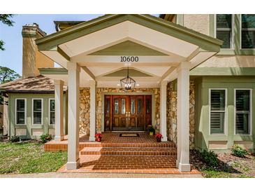 Elegant home entrance featuring a stone facade, brick steps, and a wooden double door with decorative glass panels at 10600 Indian Hills Ct, Seminole, FL 33777