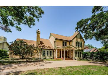 Charming two-story home featuring a stone facade, arched entrance, and mature landscaping at 10600 Indian Hills Ct, Seminole, FL 33777