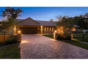 Charming home exterior featuring a brick driveway, stone accents, and professionally manicured landscaping with attractive outdoor lighting at 113 Garland Cir, Palm Harbor, FL 34683
