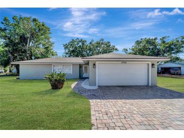 Charming single-story home featuring a well-manicured lawn and a brick-paved driveway leading to an attached two-car garage at 1968 Rolling Green Cir, Sarasota, FL 34240