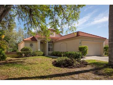 Charming single-story home featuring a red tile roof, well-maintained landscaping, and an attached two-car garage at 717 Lighthouse Dr, Tarpon Springs, FL 34689