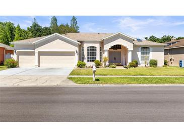 Charming single-story home with a three-car garage, manicured lawn, and inviting curb appeal at 28451 Great Bend Pl, Wesley Chapel, FL 33543