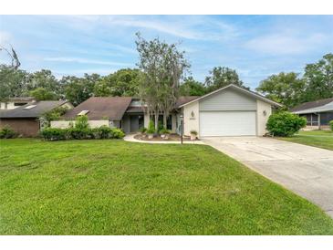Charming single-story home with a well-manicured lawn, brick facade, and inviting curb appeal at 34527 Cedarfield Dr, Dade City, FL 33523