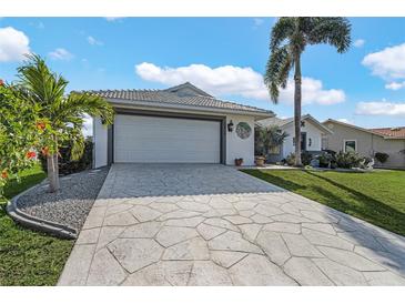 Charming single-story home with a two-car garage, a well-manicured lawn, and tropical landscaping at 3819 Barnegat Dr, Punta Gorda, FL 33950