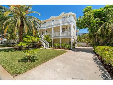 Stunning three-story beach house with a spacious driveway and tropical landscaping at 6113 Kipps Colony W Dr, Gulfport, FL 33707