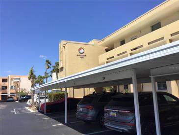 Exterior shot of condominium building featuring covered parking spaces and vibrant tropical landscaping at 7465 Bay Island S Dr # 211, South Pasadena, FL 33707