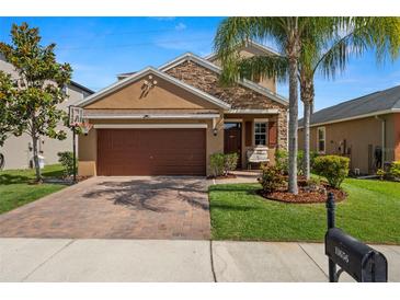 Charming home featuring a two-car garage, stone accents, a brick driveway and lush landscaping at 11656 Lake Blvd, New Port Richey, FL 34655