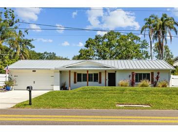 Charming single-story home with a well-manicured lawn, a metal roof, and beautiful landscaping at 1414 Sunset Ln, Lutz, FL 33549