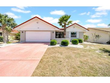 Charming single-story home with a red tile roof, palm trees, and well-maintained landscaping at 1969 Wolf Laurel Dr, Sun City Center, FL 33573