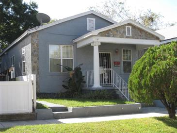 Charming single-story home featuring a stone accent wall, front porch, and well-manicured lawn at 2310 W Pine St, Tampa, FL 33607