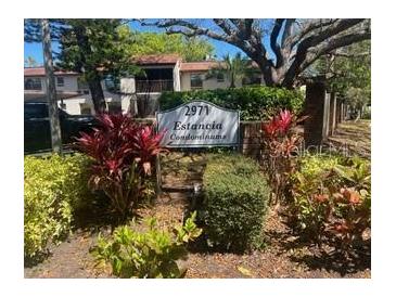Charming community entrance with colorful foliage and mature trees provides a welcoming atmosphere at 2971 Estancia Blvd # 225, Clearwater, FL 33761