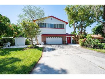 Two-story home featuring red roof, two-car garage, landscaped front yard, and mature trees at 3302 W Caracas St, Tampa, FL 33614