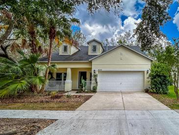 Charming light yellow single-Gathering home with a two-car garage and meticulously landscaped front yard and welcoming front porch at 6230 Gannetdale Dr, Lithia, FL 33547