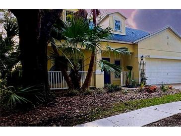 Charming yellow two-story home featuring a well-manicured lawn, palm trees, and an attached two car garage at 6230 Gannetdale Dr, Lithia, FL 33547