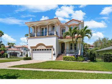 Elegant two-story home with a tile roof, balconies, lush landscaping, and a paver driveway at 108 Bermuda Ave, Tampa, FL 33606