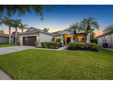 Charming home exterior featuring a well-manicured lawn, landscaped garden, and a two-car garage at 10922 Holly Cone Dr, Riverview, FL 33569