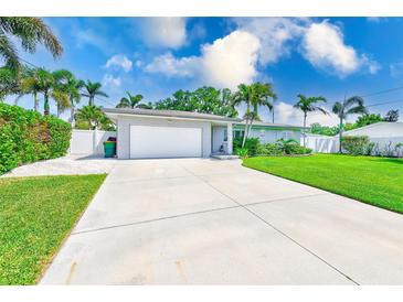 Charming single-story home featuring a well-manicured lawn and a long driveway leading to an attached garage at 11035 Huron Rd, St Petersburg, FL 33708