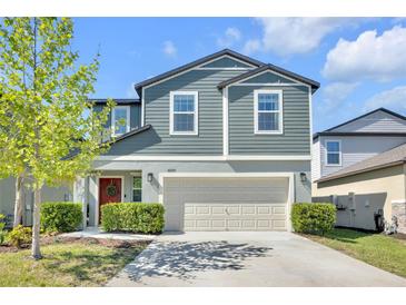 Charming two-story home with blue siding, manicured landscaping, and a welcoming red front door at 22223 Storybook Cabin Way, Land O Lakes, FL 34637