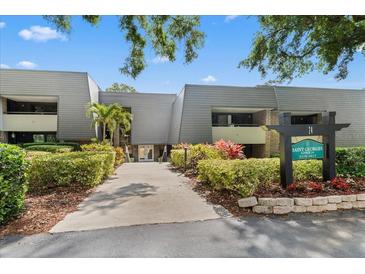 Condo complex with lush landscaping and well maintained walkway leading to the building entrance at 36750 Us 19 N # 24-104, Palm Harbor, FL 34684