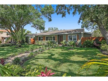 Charming single-story home featuring a lush front lawn, vibrant landscaping, and a welcoming walkway leading to the front door at 6213 10Th S Ave, Gulfport, FL 33707