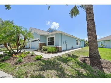 Charming single-story home featuring stone accents, lush landscaping, and a well-manicured lawn on a sunny day at 7413 Surrey Wood Ln, Apollo Beach, FL 33572