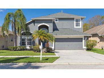 Charming two-story home featuring a manicured lawn, gray facade, arched entryway, and a two-car garage at 7725 Bingham Ct, Tampa, FL 33625
