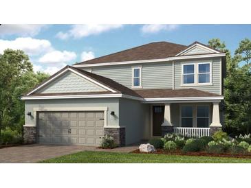Charming two-story home featuring a covered porch, a two-car garage and manicured landscaping at 1726 Trailhead Ln, Zephyrhills, FL 33541