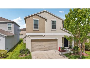 Charming two-story home featuring tan exterior, a two-car garage and manicured front lawn at 17331 White Mangrove Dr, Wimauma, FL 33598