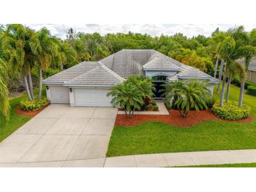 Beautiful single-story home boasts a gray tile roof, mature palms, and a spacious three-car garage at 211 Royal Bonnet Dr, Apollo Beach, FL 33572