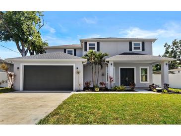 Charming two-story home featuring a manicured lawn, a two-car garage, and tasteful landscaping at 3612 W Pearl Ave, Tampa, FL 33611