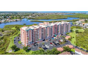 Multi-story condo building with a beautiful surrounding landscape and a parking lot full of cars at 4516 Seagull Dr # 903, New Port Richey, FL 34652