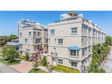 A tan multi-story townhouse complex with beautiful architectural detail and well-maintained landscaping at 409 Regent N Ln, St Petersburg, FL 33701