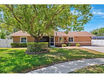 Charming single-story home featuring a lush front yard with mature landscaping and a welcoming screened entrance at 506 Spring Tree Ct, Tarpon Springs, FL 34689