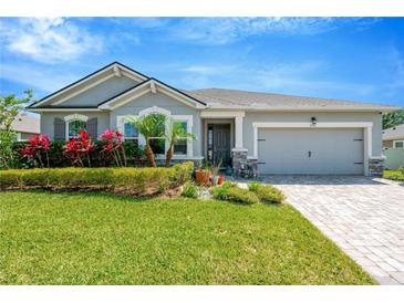 Charming single-story home with a well-manicured lawn, colorful flowers, and a brick paver driveway at 2511 Early Dawn Ct, Valrico, FL 33594