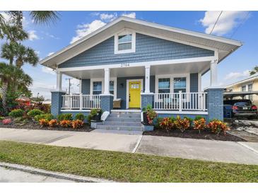 Charming home featuring a welcoming front porch, blue siding, white trim, and a cheerful yellow front door at 2704 W Main St, Tampa, FL 33607