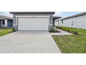 Exterior shot of a home's garage with a white garage door, concrete driveway, and landscaped front yard at 3590 Moscato Dr, Brooksville, FL 34602