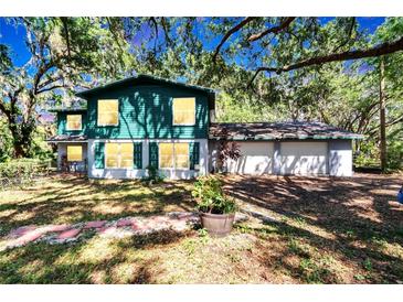 Charming two-story home with a lush, green lawn and mature trees at 9724 Hermit Hollow Ln, Gibsonton, FL 33534