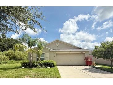 Charming single-story home featuring a well-manicured lawn, a two-car garage, and lush landscaping at 10936 Rainbow Pyrite Dr, Wimauma, FL 33598