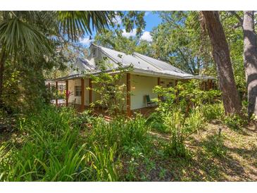 Charming home with a metal roof, a covered porch, and mature trees at 187 Sage Cir, Crystal Beach, FL 34681