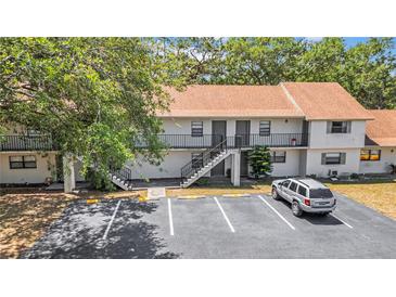 Two-story apartment complex features exterior stairs and parking with mature tree providing shade at 2122 Bradford St # 505, Clearwater, FL 33760