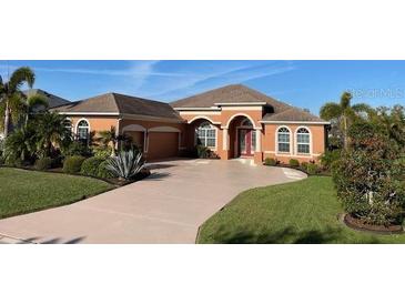 Charming, light orange single Gathering home featuring arched entry and well-manicured landscaping at 12619 50Th E Ct, Parrish, FL 34219