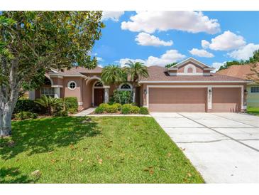Charming home featuring a three-car garage and well-manicured lawn with mature landscaping at 27054 Fordham Dr, Wesley Chapel, FL 33543