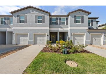 Attractive townhome exteriors with a well-kept lawn and coordinated landscaping at 36519 Garden Wall Way, Zephyrhills, FL 33541