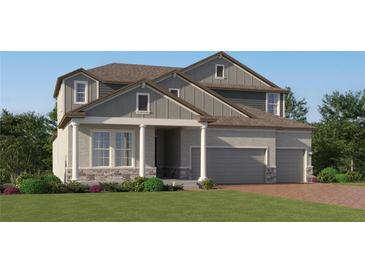 Charming two-story home with stone accents, grey siding, a well-kept lawn and three-car garage at 4807 Southern Valley Loop, Brooksville, FL 34601