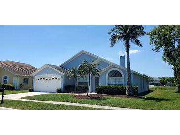 Charming one-story home features a well-manicured lawn, mature palm trees and a two-car garage in a tranquil setting at 18412 Oriole St, Lutz, FL 33558