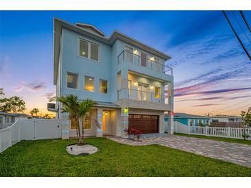Stunning three-story home with a lush lawn, a two-car garage, and a charming outdoor space with a palm tree at 326 129Th E Ave, Madeira Beach, FL 33708