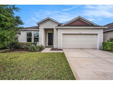 Charming single-story home featuring a well-manicured lawn, neutral paint, and an attached two-car garage at 672 Old Windsor Way, Spring Hill, FL 34609