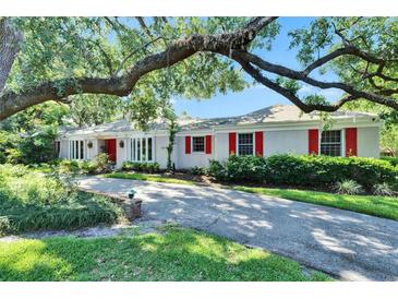 Charming single story home with white brick, red shutters, and mature landscaping at 1603 Cottagewood Dr, Brandon, FL 33510