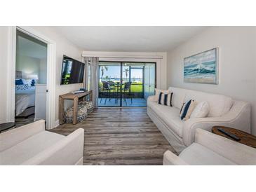 Bright living room featuring a peek of the beach, sliding glass doors, light colored couch, and light wood floors at 6265 Sun Blvd # 115, St Petersburg, FL 33715